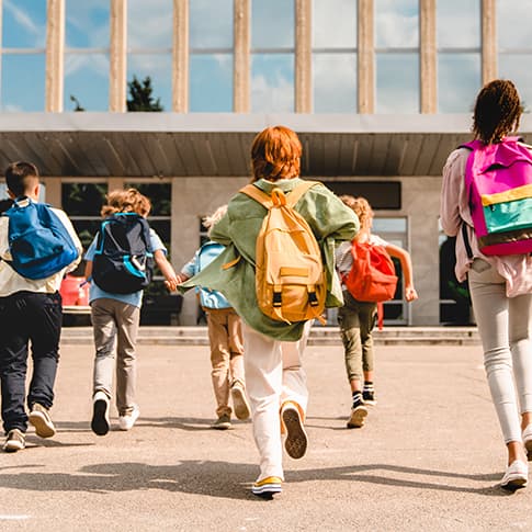 Schoolchildren run toward a school